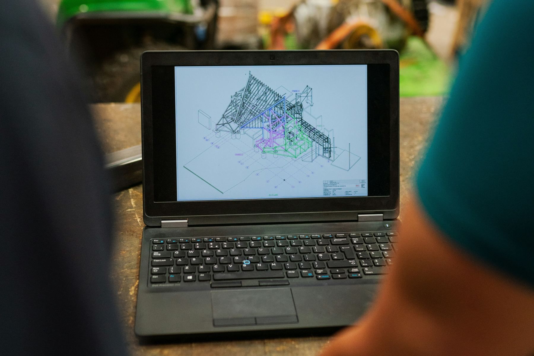 A team reviewing a 3D structural model on a laptop on the shop floor